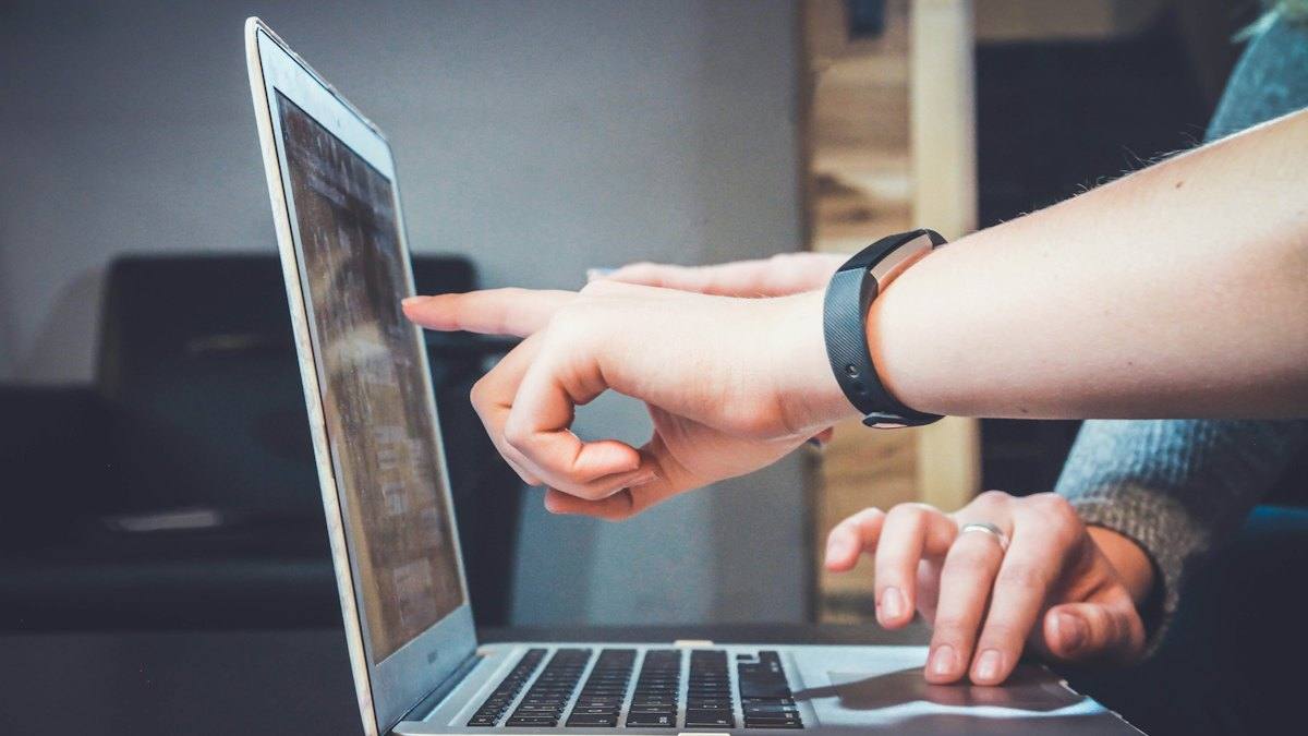 Hands pointing at a laptop screen during an online session