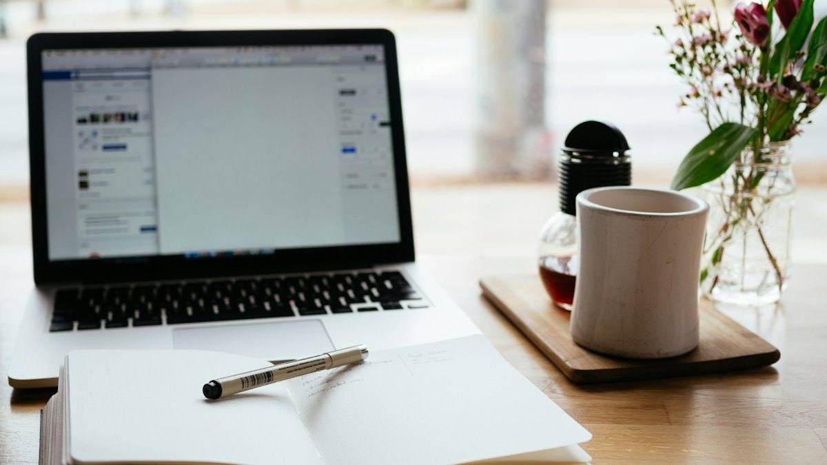 Laptop, mug and notebook on a bright desk